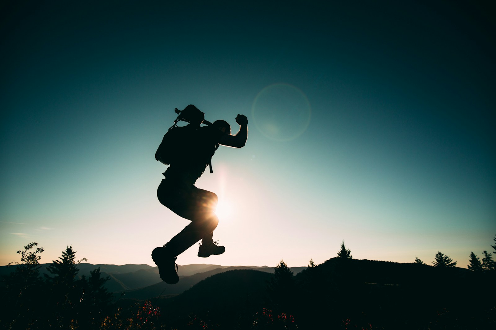 silhouette of jumping person on hill